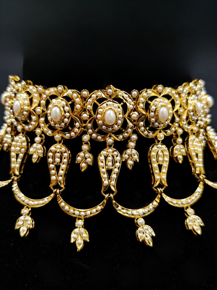 Close-up of an ornate traditional Choker white jadau gold jewellery set and jadau earrings with Pearl. Elegant reception look featuring a luxury Jadau artificial jewelry set. Close-up of high-quality Jadau artificial necklace craftsmanship.