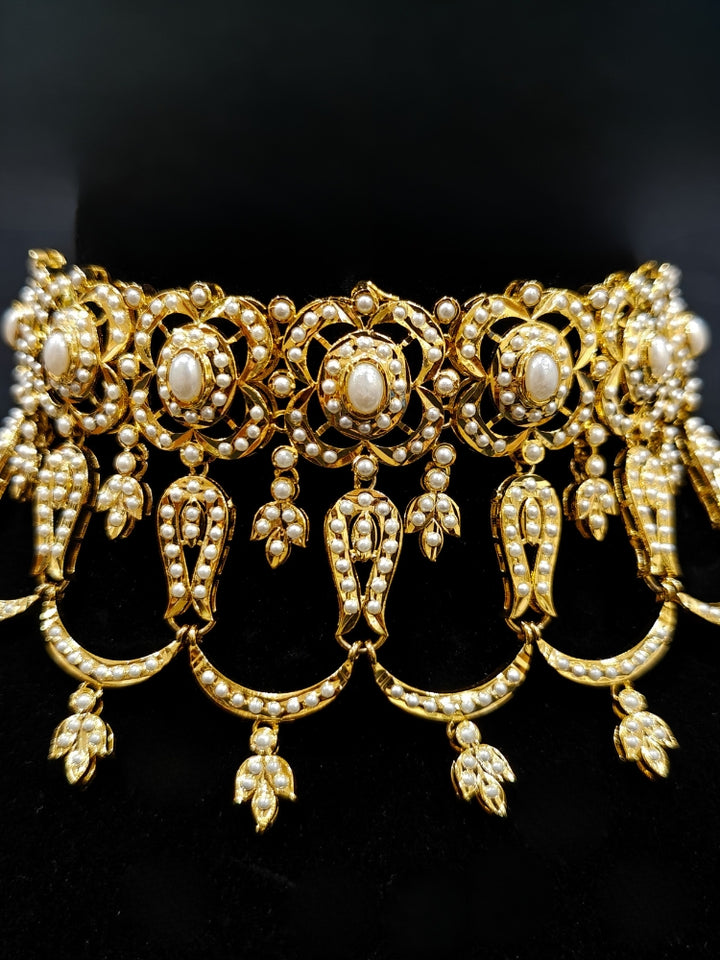 Close-up of an ornate traditional Choker white jadau gold jewellery set and jadau earrings with Pearl. Elegant reception look featuring a luxury Jadau artificial jewelry set. Close-up of high-quality Jadau artificial necklace craftsmanship.