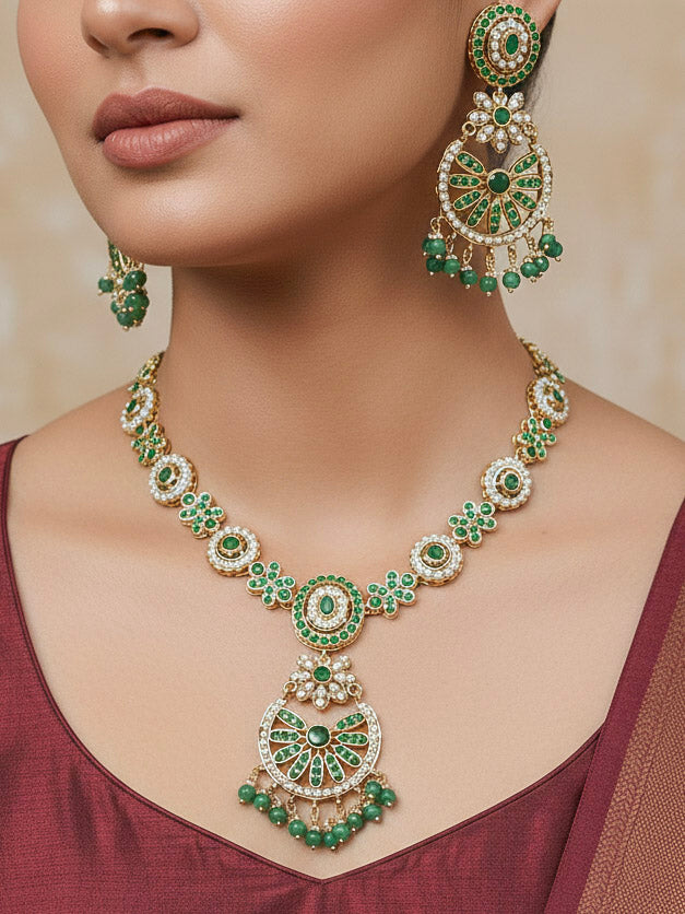 Close-up of a woman wearing an ornate traditional collar Green jadau gold jewellery set and jadau earrings with pearls and Green gemstones. Mehendi function outfit styled with a lightweight Jadau necklace. Bridal styling inspiration with a premium Jadau imitation necklace.