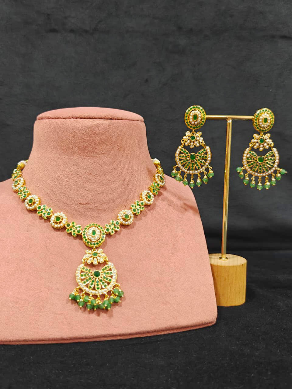 Close-up of an ornate traditional collar Green jadau gold jewellery set and jadau earrings with pearls and Green gemstones. Mehendi function outfit styled with a lightweight Jadau necklace. Close-up of high-quality Jadau artificial necklace craftsmanship.