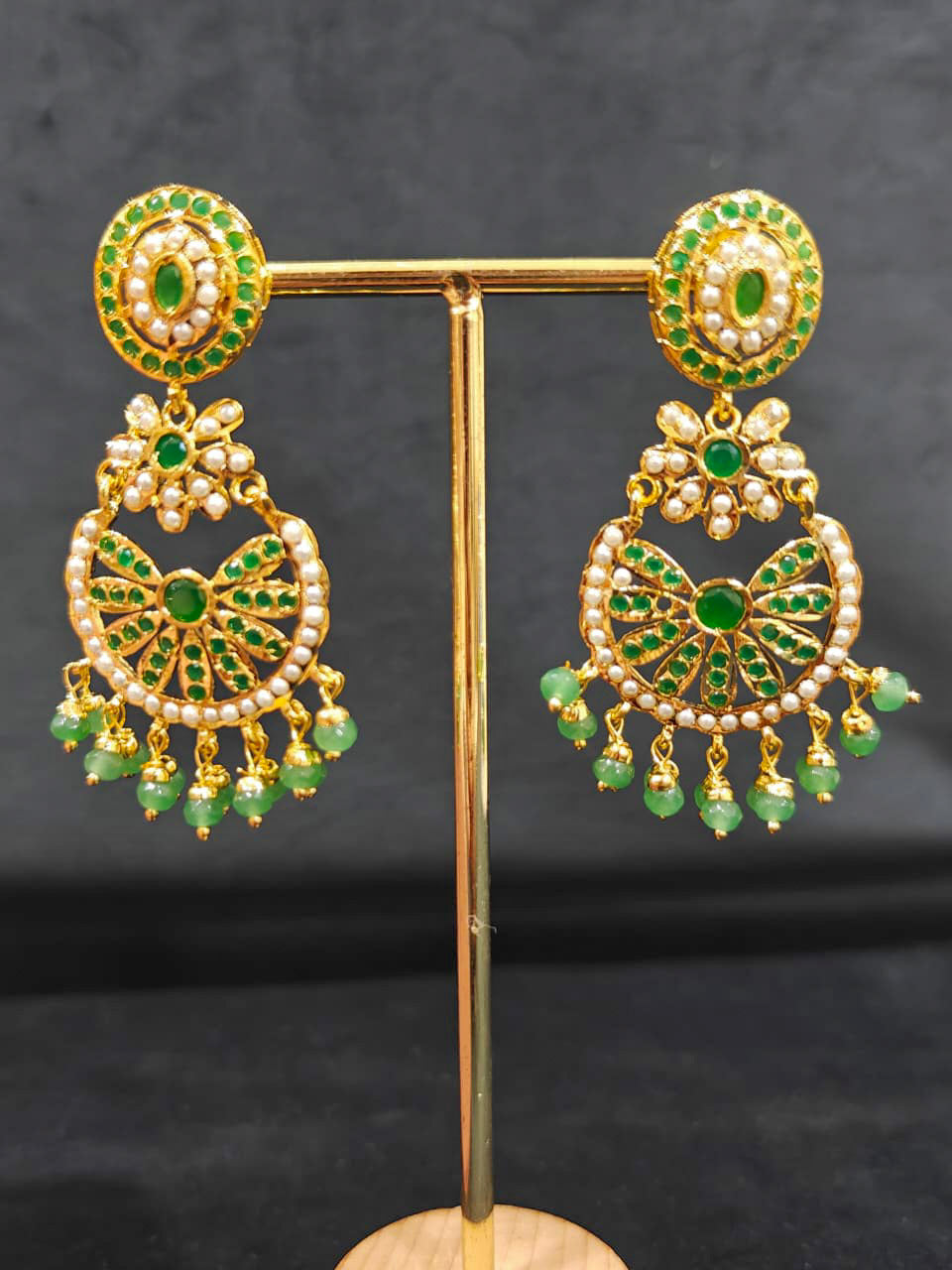 Close-up of an ornate traditional collar Green jadau gold jewellery set and jadau earrings with pearls and Green gemstones. Mehendi function outfit styled with a lightweight Jadau necklace. Close-up of high-quality Jadau artificial necklace craftsmanship.