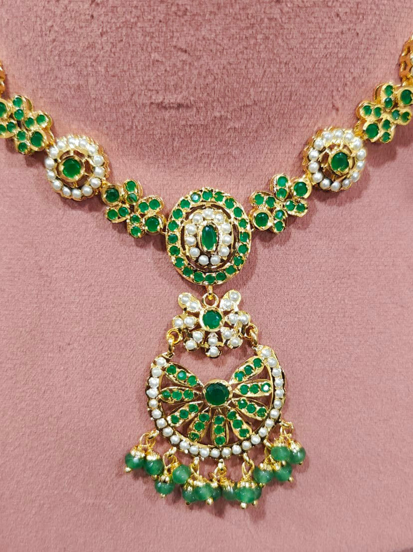 Close-up of an ornate traditional collar Green jadau gold jewellery set and jadau earrings with pearls and Green gemstones. Mehendi function outfit styled with a lightweight Jadau necklace. Close-up of high-quality Jadau artificial necklace craftsmanship.