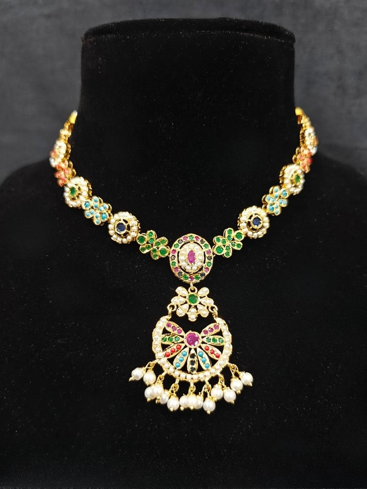 Close-up of an ornate traditional collar Navratan jadau gold jewellery set and jadau earrings with pearls and Navratan gemstones. A royal Jadau necklace for festive events in India. Styling inspiration with a premium Jadau imitation necklace.