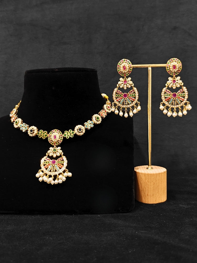 Close-up of an ornate traditional collar Navratan jadau gold jewellery set and jadau earrings with pearls and Navratan gemstones. A royal Jadau necklace for festive events in India. Styling inspiration with a premium Jadau imitation necklace.