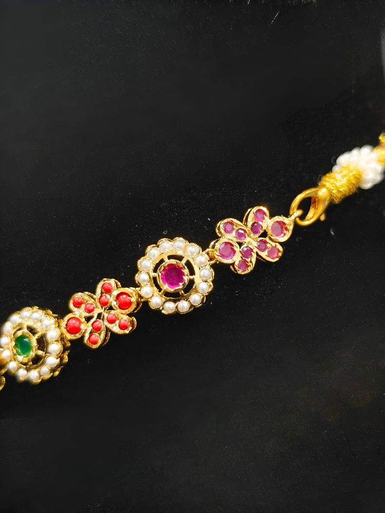 Close-up of an ornate traditional collar Navratan jadau gold jewellery set and jadau earrings with pearls and Navratan gemstones. A royal Jadau necklace for festive events in India. Styling inspiration with a premium Jadau imitation necklace.