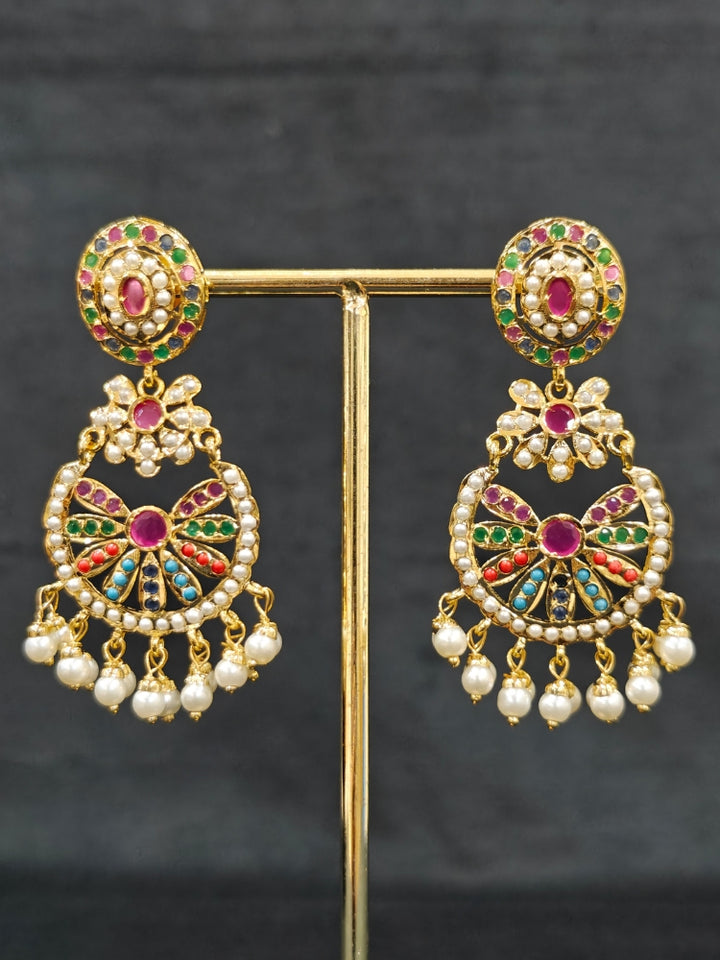 Close-up of an ornate traditional collar Navratan jadau gold jewellery set and jadau earrings with pearls and Navratan gemstones. A royal Jadau necklace for festive events in India. Styling inspiration with a premium Jadau imitation necklace.