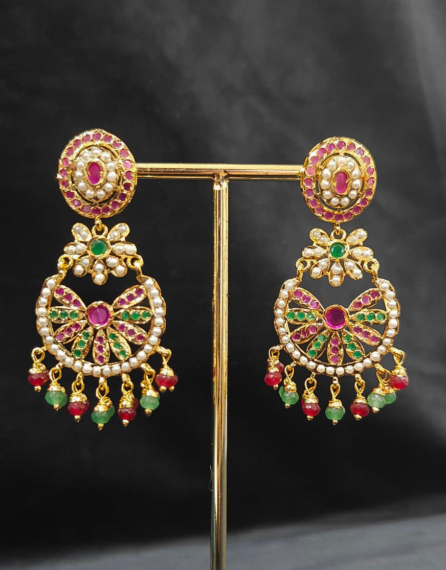 Close-up of an ornate traditional Collar Ruby Pink & Green jadau gold jewellery set and jadau earrings with pearls and Color Stone. Elegant  look featuring a luxury Jadau artificial jewelry set. Close-up of high-quality Jadau artificial necklace craftsmanship.