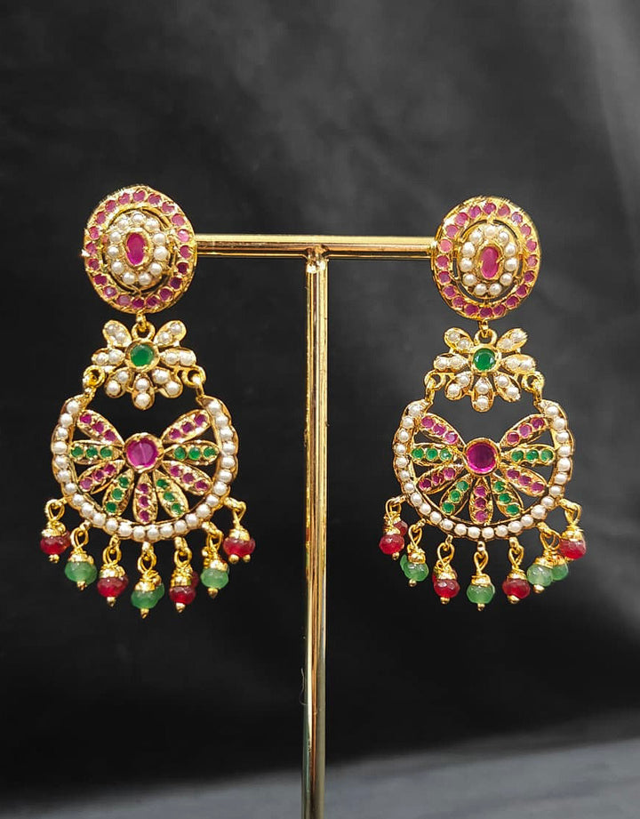 Close-up of an ornate traditional Collar Ruby Pink & Green jadau gold jewellery set and jadau earrings with pearls and Color Stone. Elegant  look featuring a luxury Jadau artificial jewelry set. Close-up of high-quality Jadau artificial necklace craftsmanship.