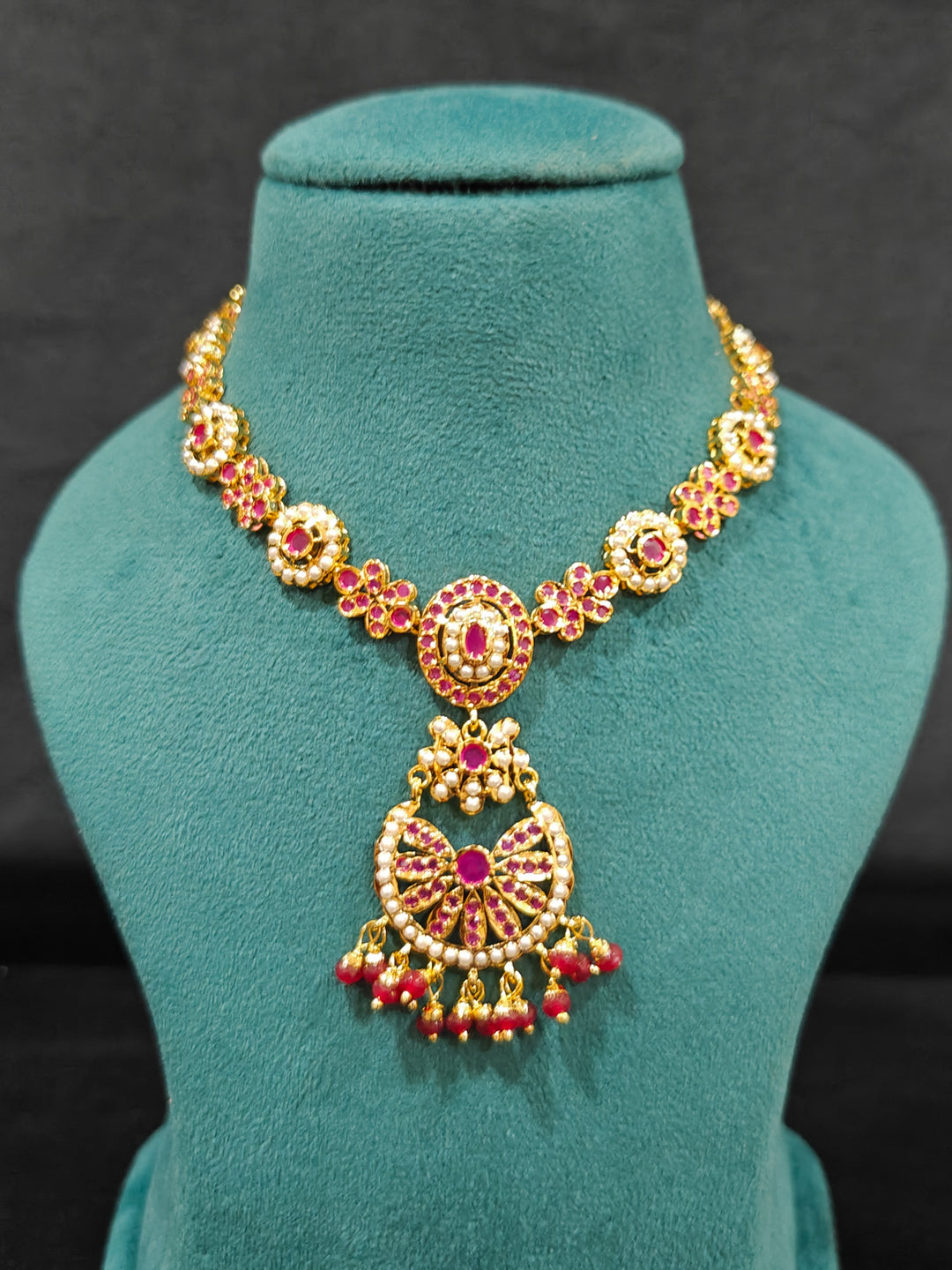 Close-up of an ornate traditional Ruby Pink jadau gold jewellery set and jadau earrings with beads and gemstones. Perfect Jadau necklace set for weddings and festivals. Mehendi function outfit styled with a lightweight Jadau necklace.