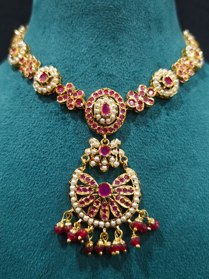 Close-up of an ornate traditional Ruby Pink jadau gold jewellery set and jadau earrings with beads and gemstones. Perfect Jadau necklace set for weddings and festivals. Mehendi function outfit styled with a lightweight Jadau necklace.