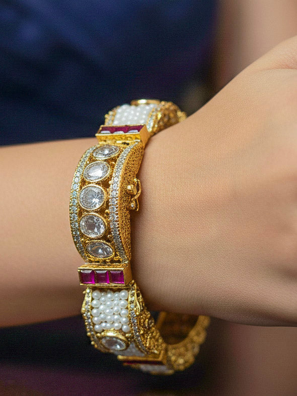 Close-up of a woman wearing an ornate Traditional American Diamond Bracelet with Gold Polish, American Diamond, Colored Stones, Pearls and Filigree Work. Festive outfit paired with a premium imitation American Diamond bracelet in India. Close-up of a high-quality imitation bracelet for festive wear.