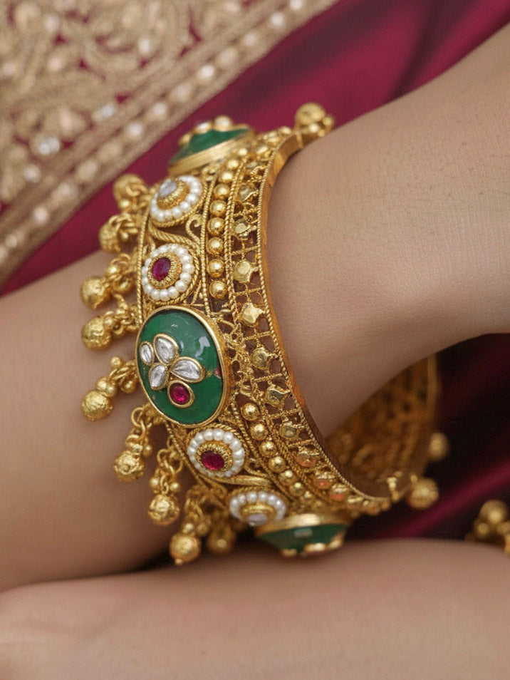 Close-up of a woman wearing an ornate traditional Mint Green Heritage gold Bangle with Colored Stones , Pearls and Kundan. Woman wearing a heritage-inspired artificial Bangles for wedding festivities. Luxury artificial Heritage bangles styled for a wedding function.