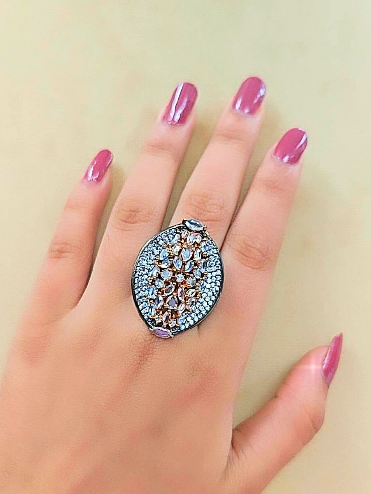 The Sasha Ring, featuring intricate gold and silver detailing with jeweled accents, is displayed on a girls hand —a perfect American Diamond cocktail ring for your wedding ceremony dress.