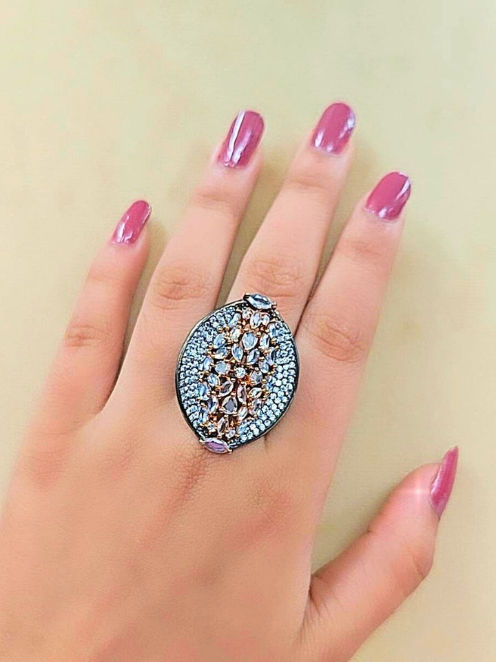 The Sasha Ring, featuring intricate gold and silver detailing with jeweled accents, is displayed on a girls hand —a perfect American Diamond cocktail ring for your wedding ceremony dress.