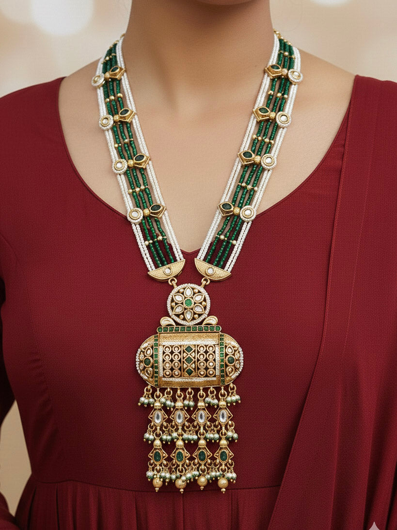 Close-up of a woman wearing an ornate traditional Dark Green Rajwadi gold Long jewellery set and earrings  with Pearls and Hydro Crystal. Woman styled in a royal Rajwadi artificial necklace set for a traditional Indian Festives. Model wearing a royal Rajwadi necklace set for Wedding celebrations in India.
