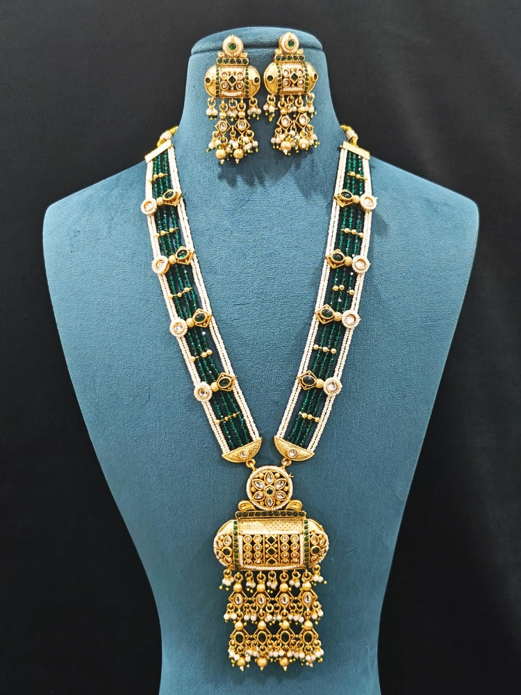 Close-up of an ornate traditional Dark Green Rajwadi gold Long jewellery set and earrings  with Pearls and Hydro Crystal. Festive look completed with a luxury Rajwadi imitation necklace. Wedding guest styling a Rajwadi artificial necklace.