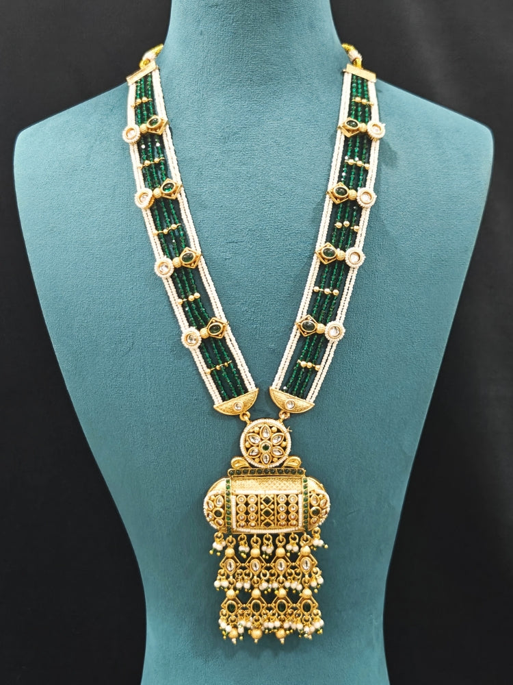 Close-up of an ornate traditional Dark Green Rajwadi gold Long jewellery set and earrings  with Pearls and Hydro Crystal. Festive look completed with a luxury Rajwadi imitation necklace. Wedding guest styling a Rajwadi artificial necklace.