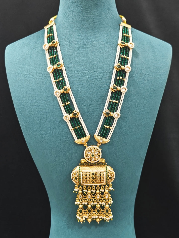 Close-up of an ornate traditional Dark Green Rajwadi gold Long jewellery set and earrings  with Pearls and Hydro Crystal. Festive look completed with a luxury Rajwadi imitation necklace. Wedding guest styling a Rajwadi artificial necklace.