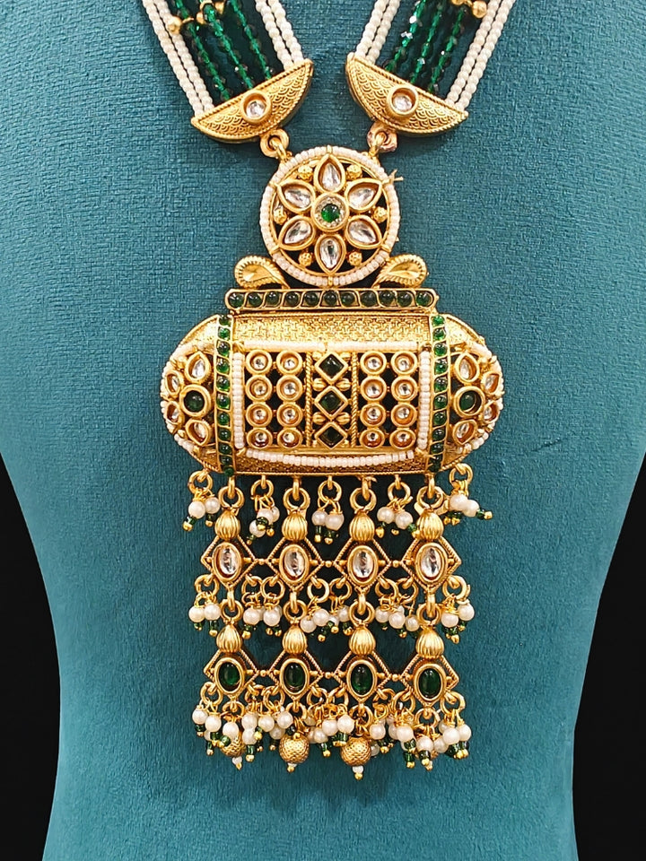 Close-up of an ornate traditional Dark Green Rajwadi gold Long jewellery set and earrings  with Pearls and Hydro Crystal. Festive look completed with a luxury Rajwadi imitation necklace. Wedding guest styling a Rajwadi artificial necklace.