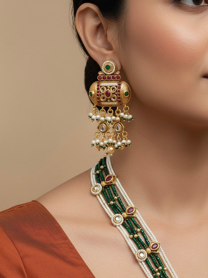 Close-up of a woman wearing an ornate traditional Red and Green Rajwadi gold Long jewellery set and earrings  with Pearls and Hydro Crystal. Bride wearing a premium Rajwadi necklace with a saree for her reception. Festive Diwali outfit enhanced with a Rajwadi artificial necklace.