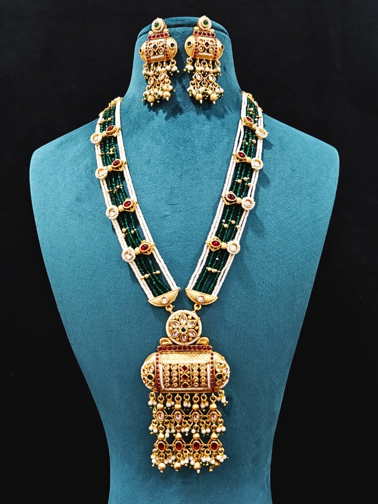 Close-up of an ornate traditional Red and Green Rajwadi gold Long jewellery set and earrings  with Pearls and Hydro Crystal. Festive Diwali outfit enhanced with a Rajwadi artificial necklace. Close-up of detailed Rajwadi craftsmanship in artificial jewelry.