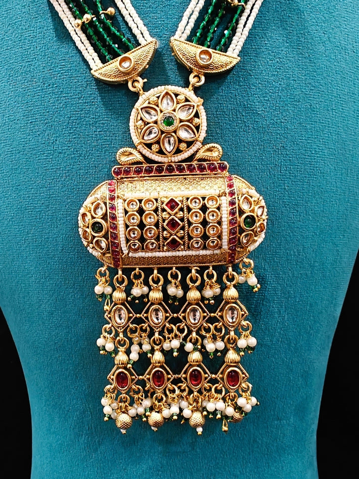 Close-up of an ornate traditional Red and Green Rajwadi gold Long jewellery set and earrings  with Pearls and Hydro Crystal. Festive Diwali outfit enhanced with a Rajwadi artificial necklace. Close-up of detailed Rajwadi craftsmanship in artificial jewelry.