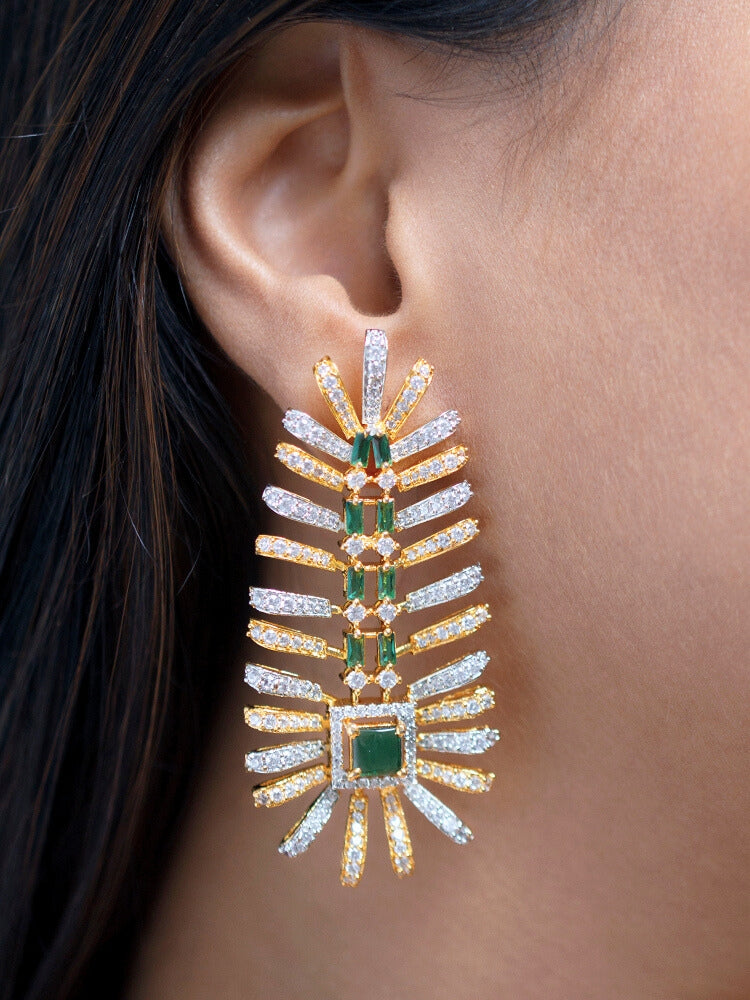 A woman in a strapless black dress showcases the Selvaggia long Necklace Set, featuring sparkling American Diamonds and white stones, with large earrings and an intricate green necklace adorned with gemstone accents.