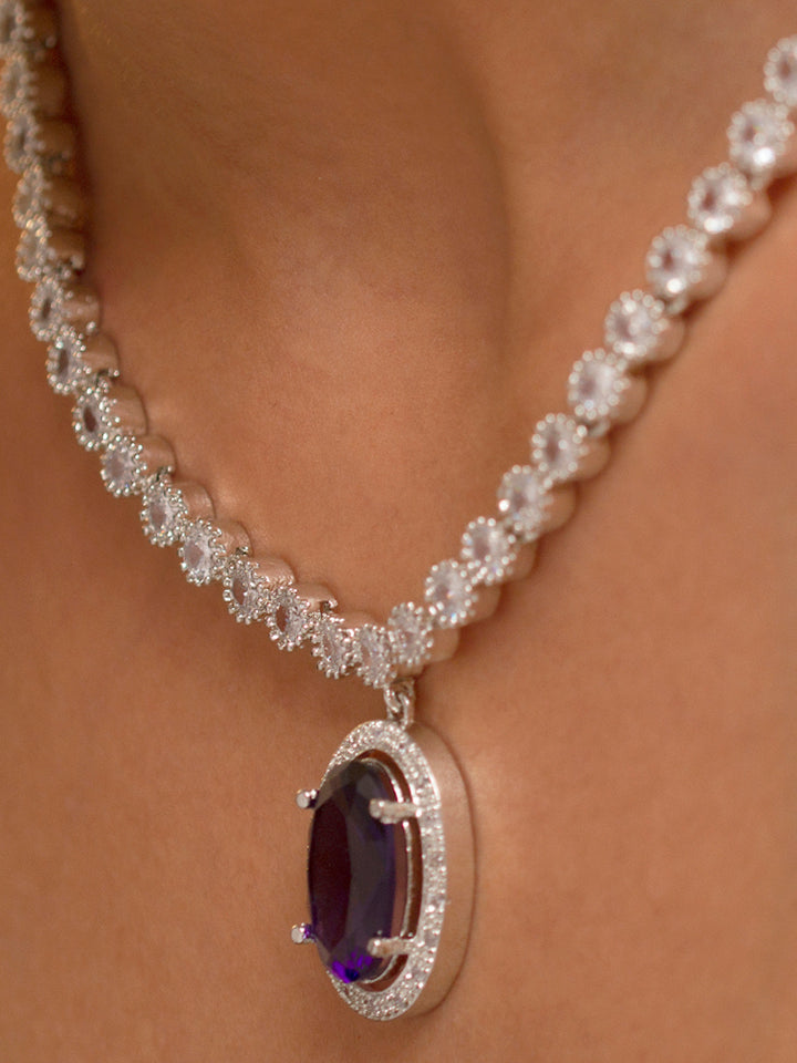 A beautiful woman wearing an elegant artificial diamond necklace with purple colored stone and matching earrings. This premium artificial diamond jewelry set is perfect for special occasions, from Indian weddings to engagement parties, offering sophisticated glamour without the high price tag.