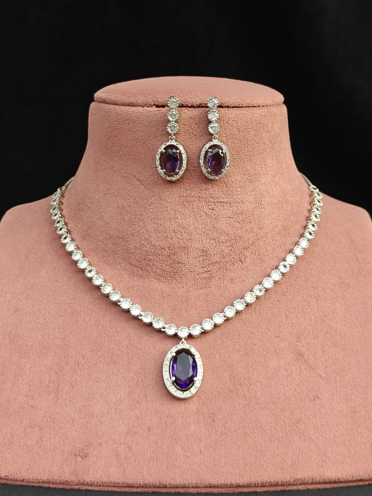 Close-up of a woman wearing an ornate Western Purple (Silver Gold) Collar jewellery set and earrings with American Diamond and Colored Stones. Reception-ready look featuring a statement American diamond jewelry set. Close-up of a cocktail party look featuring a premium American diamond necklace.