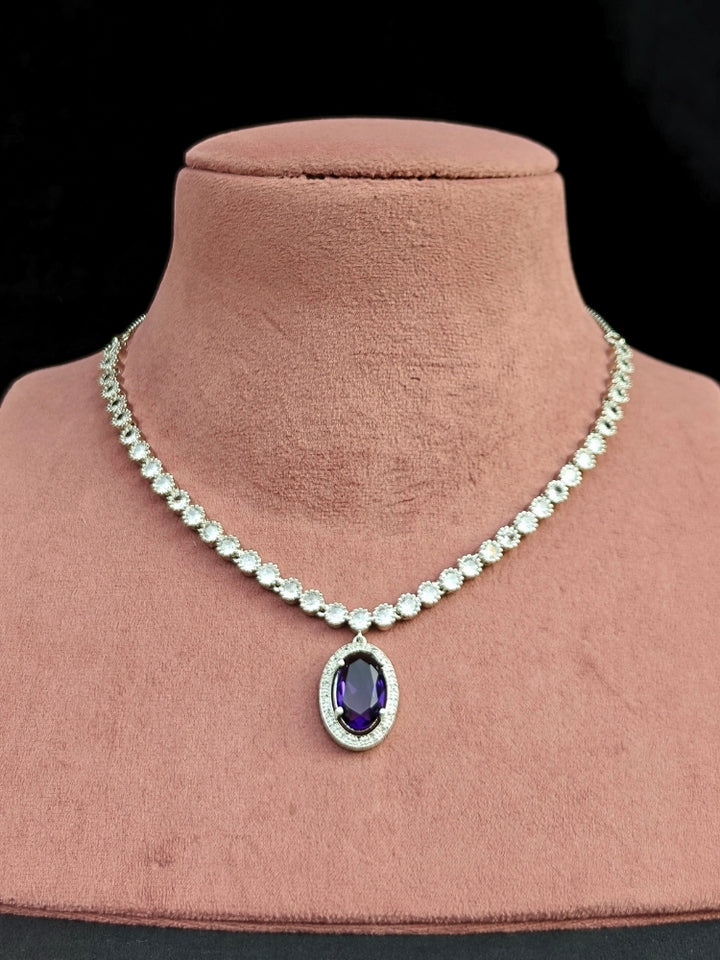 Close-up of a woman wearing an ornate Western Purple (Silver Gold) Collar jewellery set and earrings with American Diamond and Colored Stones. Reception-ready look featuring a statement American diamond jewelry set. Close-up of a cocktail party look featuring a premium American diamond necklace.