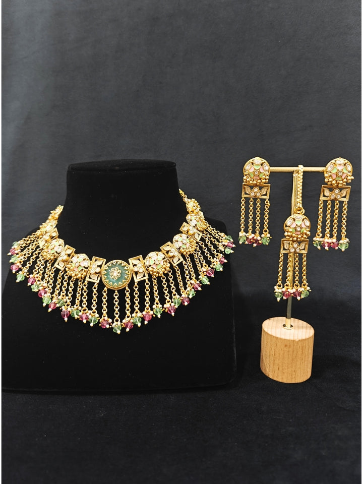Close-up of an ornate traditional Mint Pink and Green Heritage gold Collar jewellery set and earrings and maangtikka with Beads, Colored Stones and Kundan.  A heritage-inspired artificial necklace for wedding festivities. Saree styling inspiration with a traditional heritage necklace.