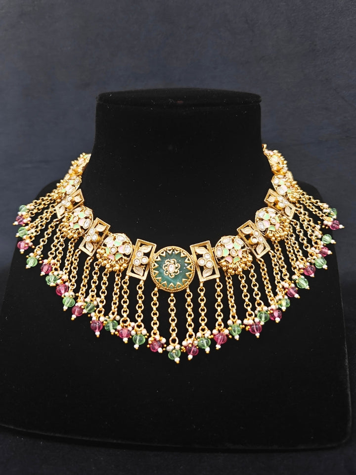 Close-up of an ornate traditional Mint Pink and Green Heritage gold Collar jewellery set and earrings and maangtikka with Beads, Colored Stones and Kundan.  A heritage-inspired artificial necklace for wedding festivities. Saree styling inspiration with a traditional heritage necklace.