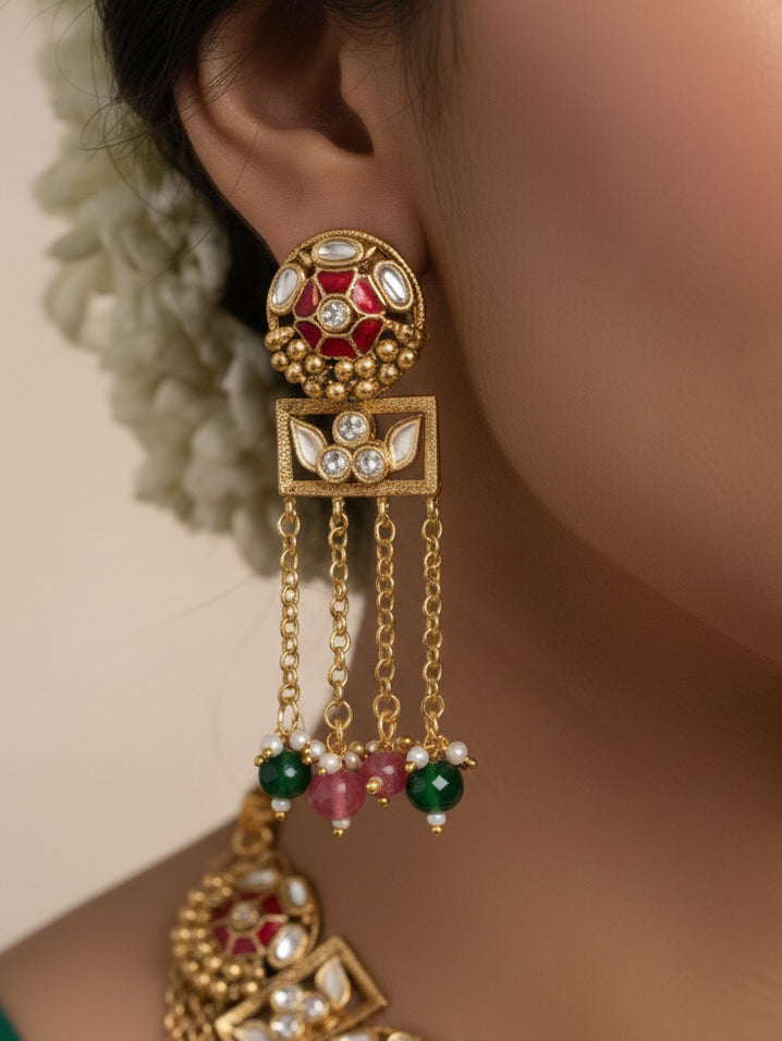 Close-up of a woman wearing an ornate traditional Red and Green Heritage gold Collar jewellery set and earrings and maangtikka with Beads, Colored Stones and Kundan. Woman wearing a heritage-inspired artificial necklace for wedding festivities. Saree styling inspiration with a traditional heritage necklace.