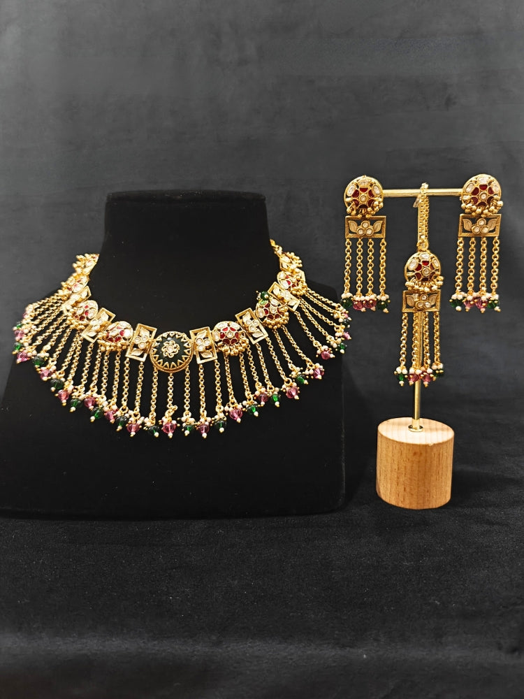 Close-up of an ornate traditional Red and Green Heritage gold Collar jewellery set and earrings and maangtikka with Beads, Colored Stones and Kundan. A heritage-inspired artificial necklace for wedding festivities. Saree styling inspiration with a traditional heritage necklace.
