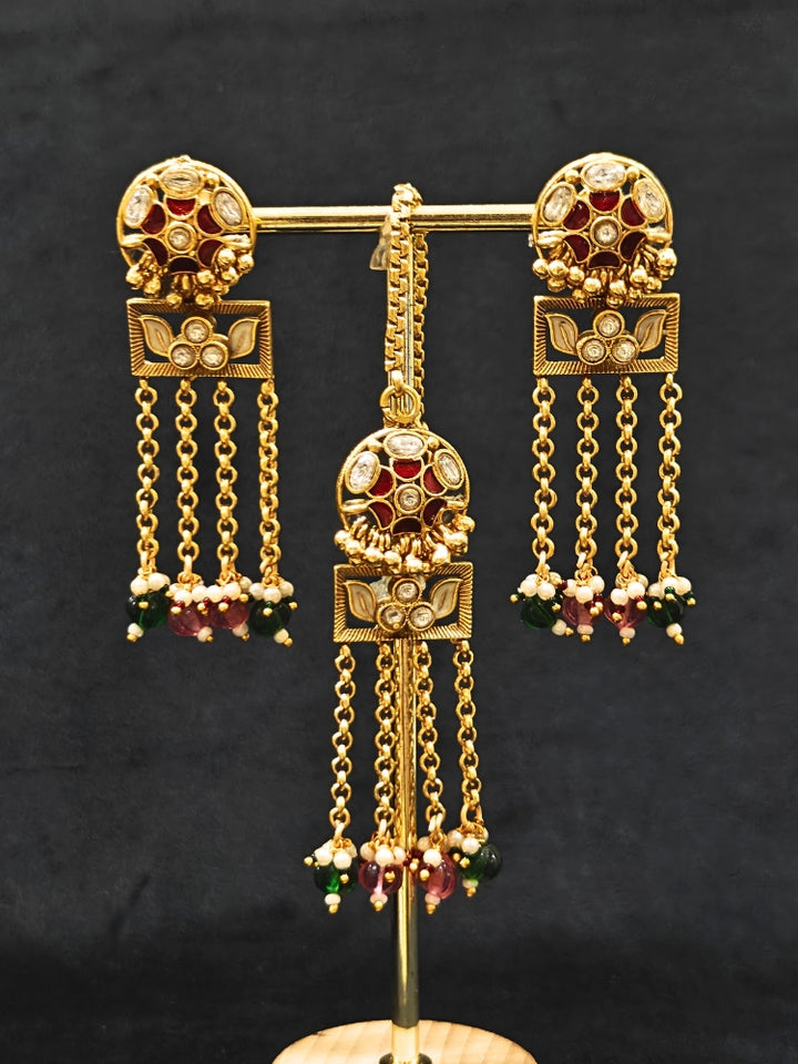Close-up of an ornate traditional Red and Green Heritage gold Collar jewellery set and earrings and maangtikka with Beads, Colored Stones and Kundan. A heritage-inspired artificial necklace for wedding festivities. Saree styling inspiration with a traditional heritage necklace.