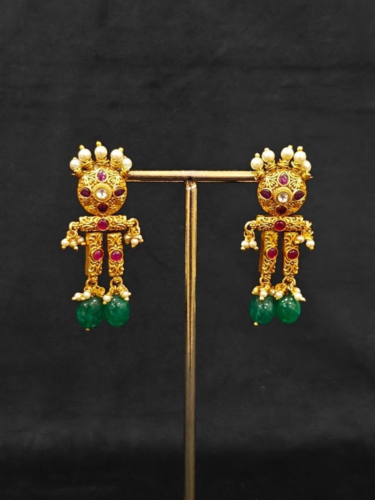 Close-up of an ornate traditional (Gold Polish) Choker jewellery set and earrings with Pearls, Green Beads and Colored Stones. Wedding guest look featuring a statement imitation jewelry set. Wedding guest outfit enhanced with elegant artificial jewelry.