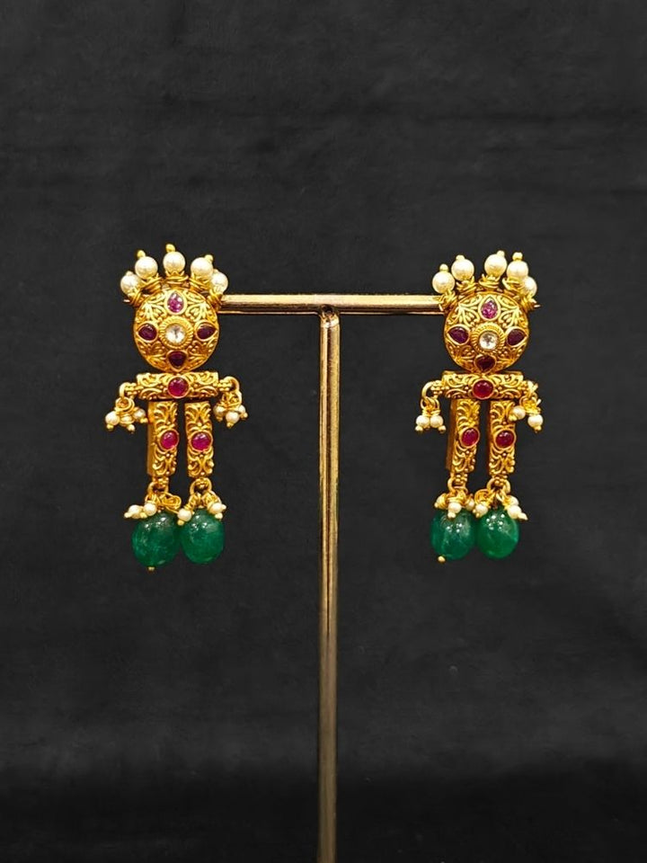 Close-up of an ornate traditional (Gold Polish) Choker jewellery set and earrings with Pearls, Green Beads and Colored Stones. Wedding guest look featuring a statement imitation jewelry set. Wedding guest outfit enhanced with elegant artificial jewelry.