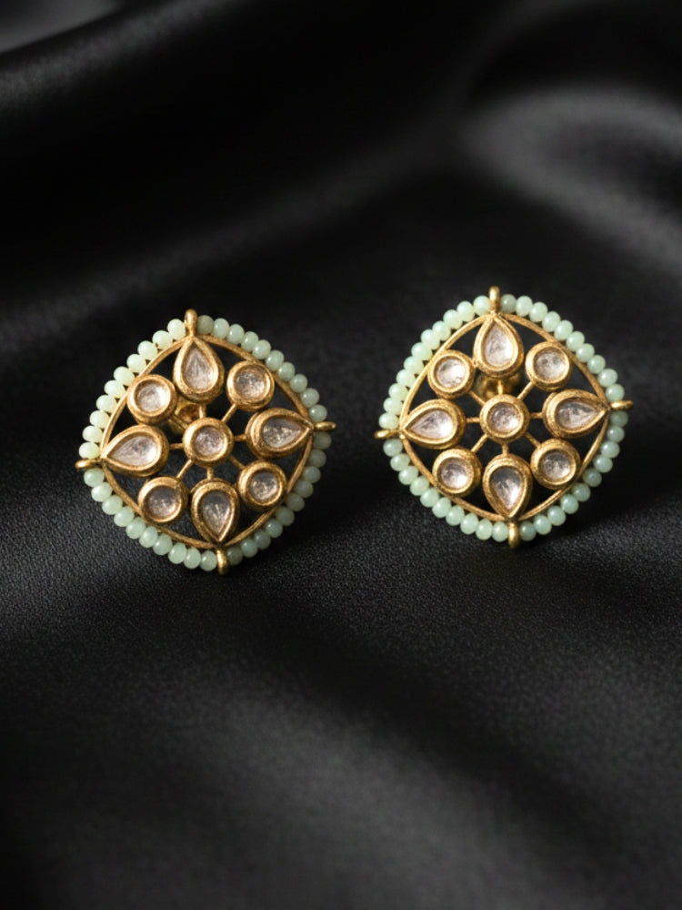 Close-up of an ornate traditional (Gold Polish) Mint Green Studs Earrings with Kundan, Crystal Beads and Green Colored Stones in Mid. Mehendi ceremony look completed with a handcrafted Kundan Studs Earrings. Festive Diwali outfit paired with a premium Kundan Studs Earrings.