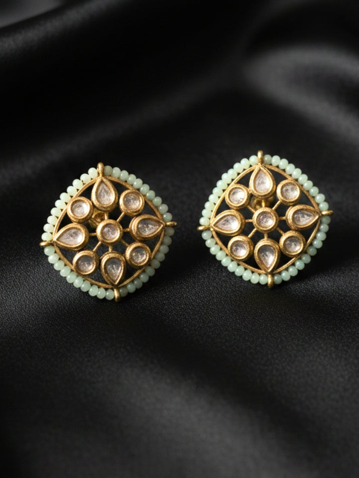 Close-up of an ornate traditional (Gold Polish) Mint Green Studs Earrings with Kundan, Crystal Beads and Green Colored Stones in Mid. Mehendi ceremony look completed with a handcrafted Kundan Studs Earrings. Festive Diwali outfit paired with a premium Kundan Studs Earrings.