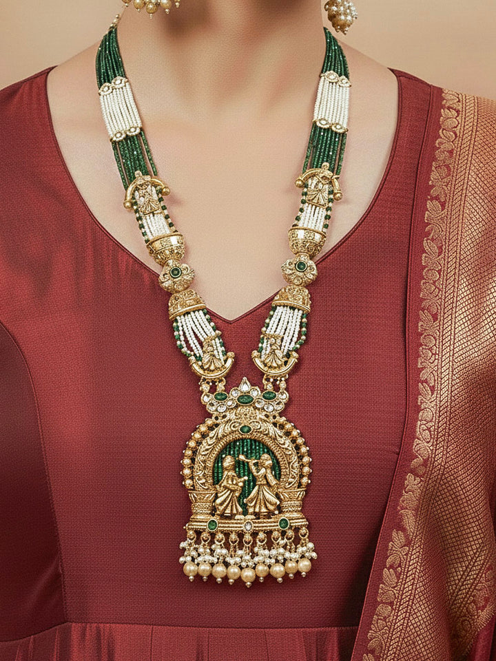 Close-up of a woman wearing an ornate traditional Dark Green Rajwadi gold Long jewellery set and earrings  with Pearls, Hydro Crystal and Bandhai Work. Woman styled in a royal Rajwadi artificial necklace set for a traditional Indian wedding.
Woman wearing a bridal Rajwadi necklace for a reception function.