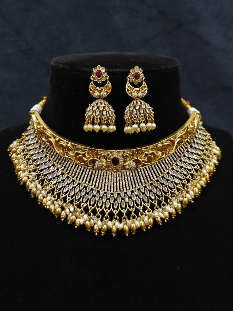 Close-up of an ornate traditional (Gold Polish) Choker jewellery set and earrings with American Diamond and Pearls. A woman wearing a luxury American diamond necklace set styled beautifully for a wedding guest look in India. Elegant wedding jewelry look featuring a premium artificial American diamond necklace.