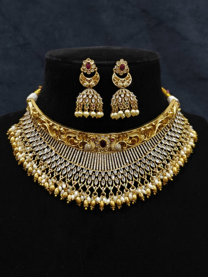 Close-up of an ornate traditional (Gold Polish) Choker jewellery set and earrings with American Diamond and Pearls. A woman wearing a luxury American diamond necklace set styled beautifully for a wedding guest look in India. Elegant wedding jewelry look featuring a premium artificial American diamond necklace.