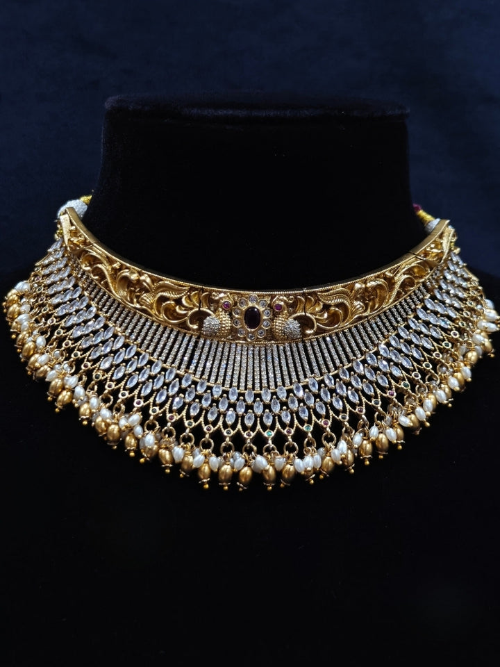 Close-up of an ornate traditional (Gold Polish) Choker jewellery set and earrings with American Diamond and Pearls. A woman wearing a luxury American diamond necklace set styled beautifully for a wedding guest look in India. Elegant wedding jewelry look featuring a premium artificial American diamond necklace.