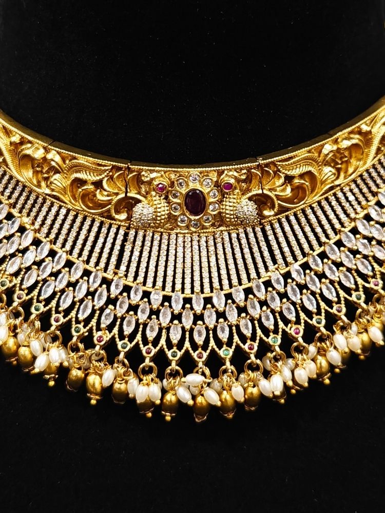 Close-up of an ornate traditional (Gold Polish) Choker jewellery set and earrings with American Diamond and Pearls. A woman wearing a luxury American diamond necklace set styled beautifully for a wedding guest look in India. Elegant wedding jewelry look featuring a premium artificial American diamond necklace.
