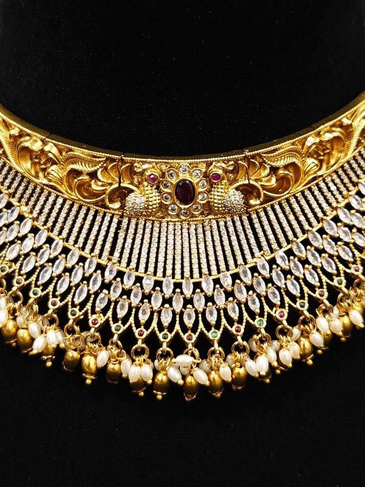Close-up of an ornate traditional (Gold Polish) Choker jewellery set and earrings with American Diamond and Pearls. A woman wearing a luxury American diamond necklace set styled beautifully for a wedding guest look in India. Elegant wedding jewelry look featuring a premium artificial American diamond necklace.