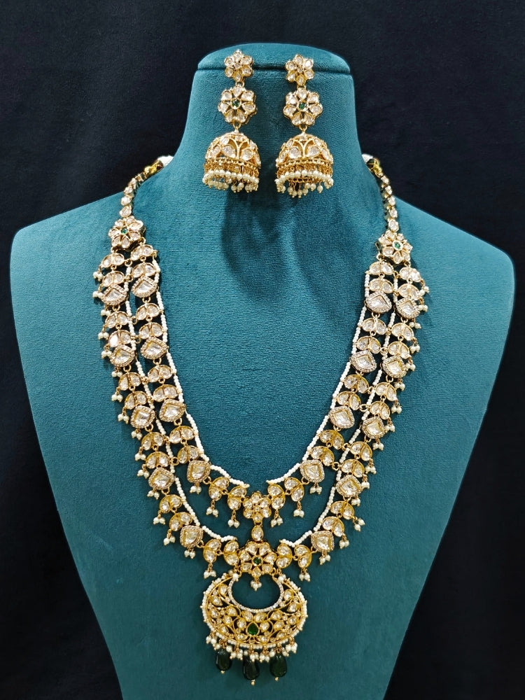 Close-up of an ornate traditional (Gold Polish) Green Long jewellery set and earrings with Polki, American Diamond and Pearl. Festive Diwali look enhanced with a premium Polki artificial necklace. Wedding guest outfit styled with an elegant Polki necklace set.Close-up of high-quality imitation Polki jewelry for bridal wear.