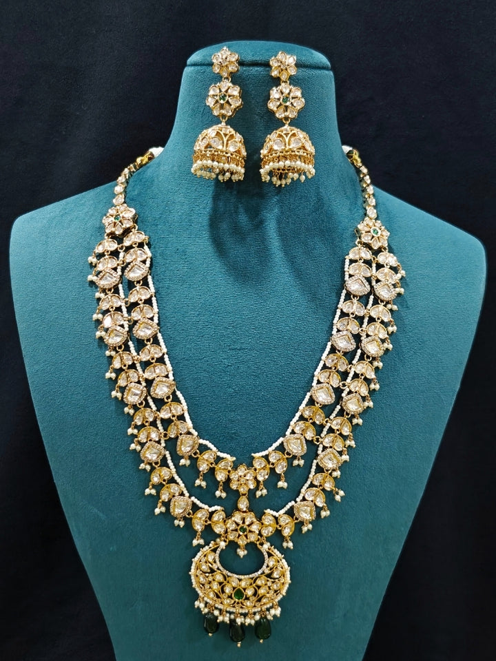Close-up of an ornate traditional (Gold Polish) Green Long jewellery set and earrings with Polki, American Diamond and Pearl. Festive Diwali look enhanced with a premium Polki artificial necklace. Wedding guest outfit styled with an elegant Polki necklace set.Close-up of high-quality imitation Polki jewelry for bridal wear.