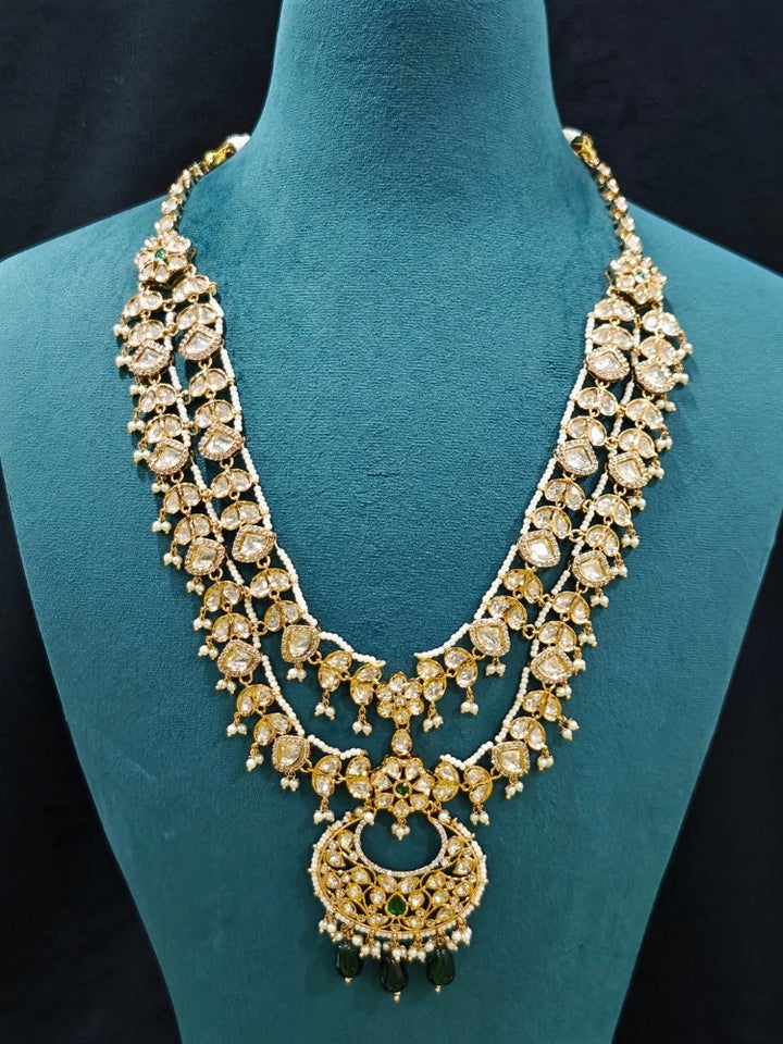 Close-up of an ornate traditional (Gold Polish) Green Long jewellery set and earrings with Polki, American Diamond and Pearl. Festive Diwali look enhanced with a premium Polki artificial necklace. Wedding guest outfit styled with an elegant Polki necklace set.Close-up of high-quality imitation Polki jewelry for bridal wear.