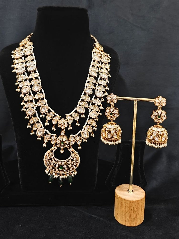 Close-up of an ornate traditional (Gold Polish) Green Long jewellery set and earrings with Polki, American Diamond and Pearl. Festive Diwali look enhanced with a premium Polki artificial necklace. Wedding guest outfit styled with an elegant Polki necklace set.Close-up of high-quality imitation Polki jewelry for bridal wear.