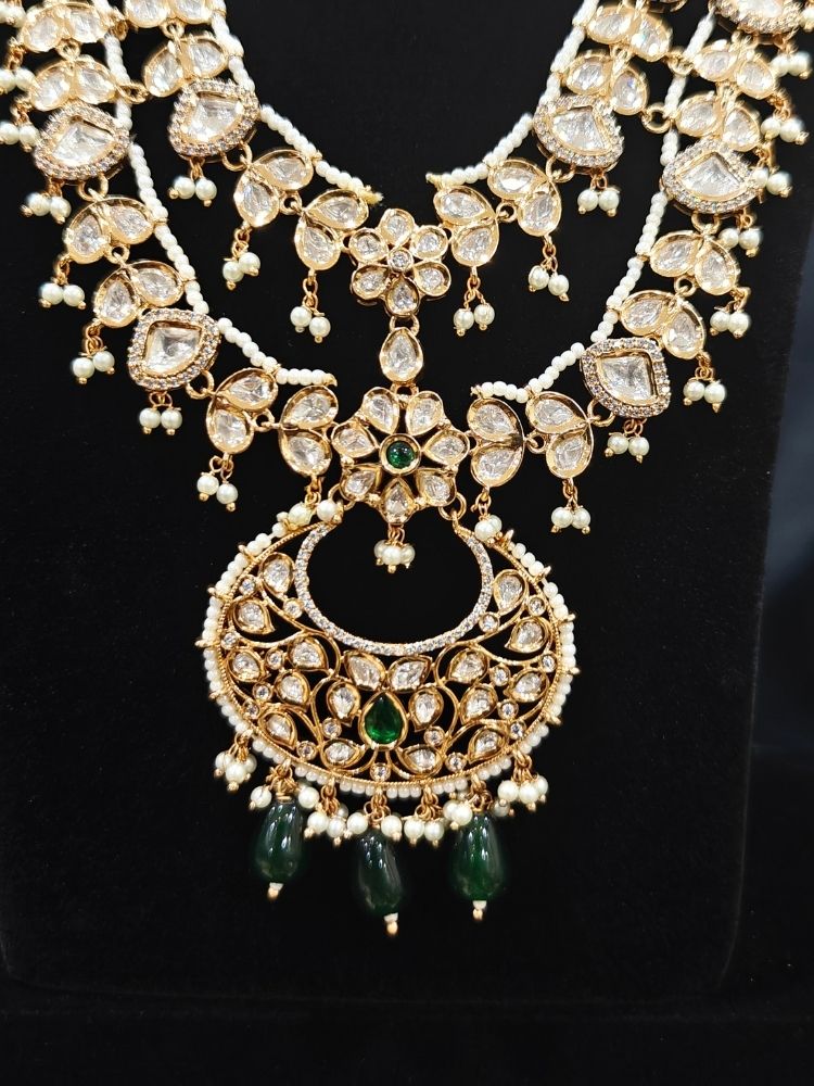 Close-up of an ornate traditional (Gold Polish) Green Long jewellery set and earrings with Polki, American Diamond and Pearl. Festive Diwali look enhanced with a premium Polki artificial necklace. Wedding guest outfit styled with an elegant Polki necklace set.Close-up of high-quality imitation Polki jewelry for bridal wear.